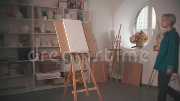 一位年轻的金发女艺术家走到画架前在画布上画素描视频的预览图