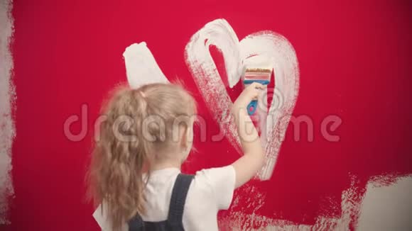 女孩正在红墙上画一颗白色的心视频的预览图