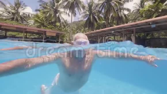 度假时一个喝醉的人正在热带岛屿的酒店室外游泳池游泳视频的预览图
