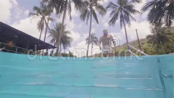 成熟男子进入水上游泳池通过楼梯在度假酒店水下景观成年人在室外游泳池游泳视频的预览图