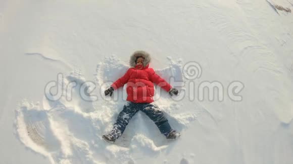 一个小男孩做一个雪天使冬季娱乐概念慢镜头视频的预览图