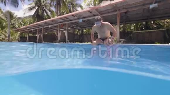 在热带小岛度假时一个留胡子的年轻人正在游泳池里潜水视频的预览图