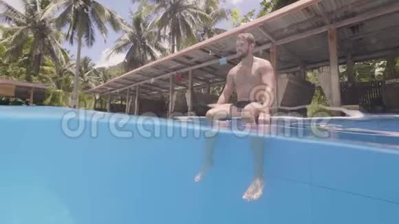 旅游青年正坐在热带岛屿的游泳池附近晒太阳视频的预览图