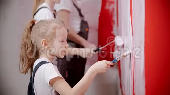 一家人正在用滚筒和刷子粉刷一面红墙视频的预览图