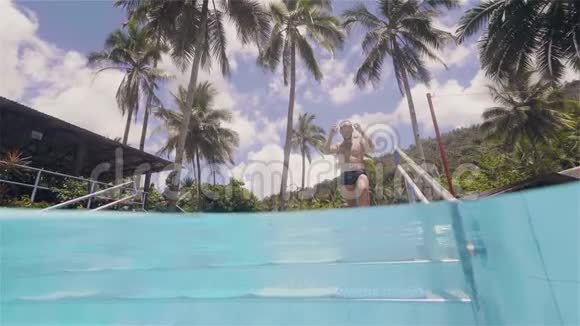 年轻人要去游泳沿着游泳池的台阶在热带岛屿上的豪华酒店休息视频的预览图