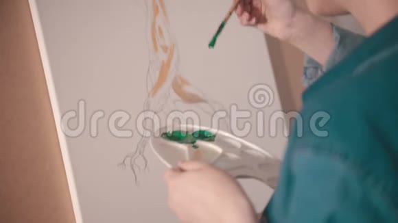 一位金发短发的年轻女子在艺术工作室里用绿色画树上枝视频的预览图