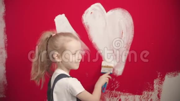 小女孩正在红墙上画一颗白色的心微笑着视频的预览图