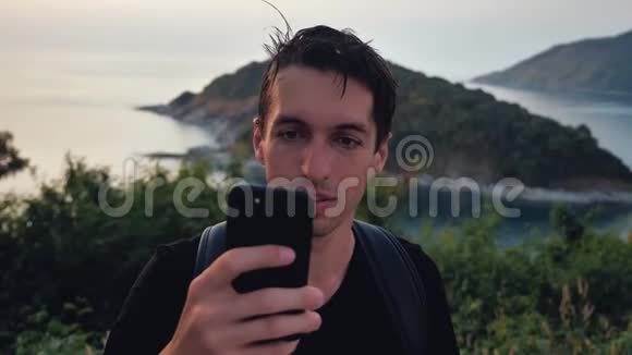 带背包的人用智能手机旅行者在山顶上的热带岛屿的背景视频的预览图