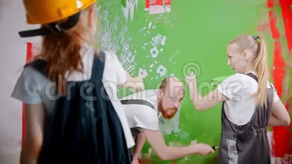 父母和女儿正在讨论如何用绿色油漆粉刷墙壁视频的预览图