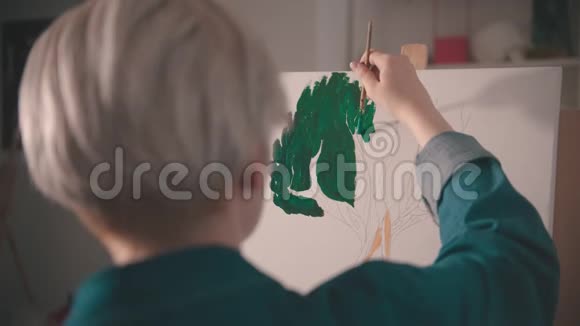 一位年轻的金发女子在画布上画着绿色视频的预览图