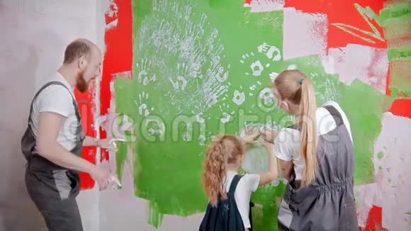 一家人用自己的手画着一面绿色的墙视频的预览图