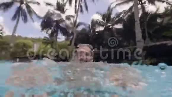 笑着长胡子的人在游泳池里跳跃溅起水花从水下缓慢地射击视频的预览图