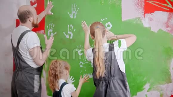 一家人把他们白色的手印放在绿色的墙上视频的预览图