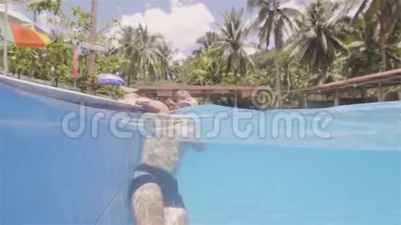 年轻的游泳运动员从度假酒店水线景观的室外游泳池出来坐在池边的胡子男视频的预览图