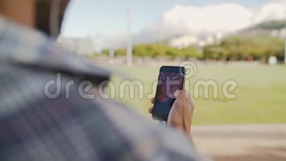 一个男人在网上聊天的肩膀上拍摄的照片用他的智能手机和他在公园的朋友打视频电话视频的预览图