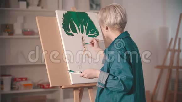 一个年轻的金发女人用颜料画树视频的预览图