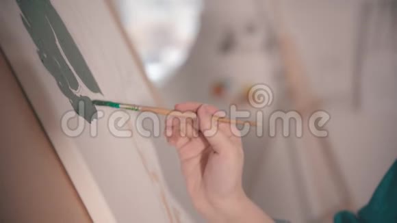 一位年轻漂亮的金发女人在画布上画着一幅绿色的画视频的预览图