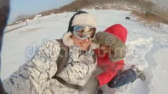 一个年轻人和他的小儿子在大雪后的一场雪中玩得很开心冬季概念慢镜头视频的预览图
