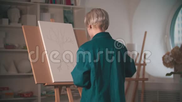 一位年轻的女艺术家开始在艺术工作室用米色画她的素描视频的预览图