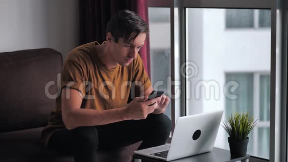 快乐的年轻人用笔记本电脑做电子商务在家里坐在沙发上看视频电影视频的预览图