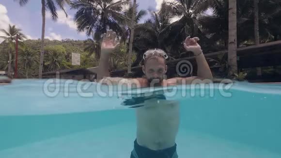 在热带小岛度假的时候大胡子的年轻快乐男子正在游泳池里泼水视频的预览图