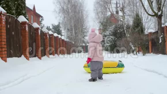 在一个下雪的冬天一个小孩试图在绳子上拉一个充气圈视频的预览图