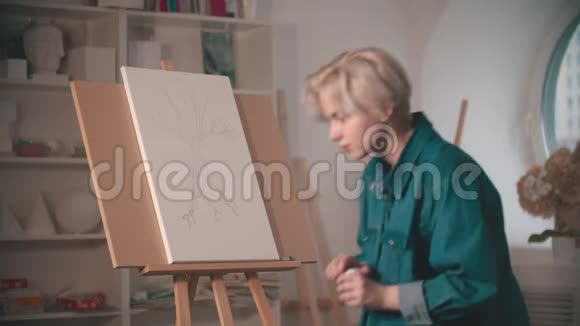 一位年轻的女艺术家打开一幅米色的画来给她的画上色视频的预览图