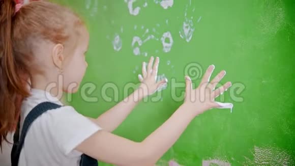 小女孩把手印贴在绿色的墙上视频的预览图