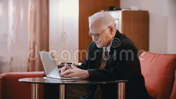 年迈的祖父穿着西装的老祖父正在电脑上打字疲倦地摘下眼镜视频的预览图