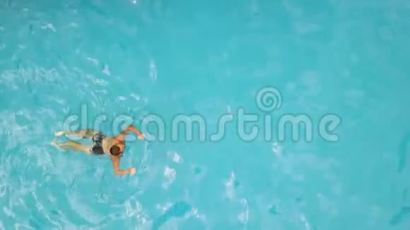 年轻人在漂浮的游泳池里游泳从上面的飞行无人机男子游泳池景水上运动视频的预览图