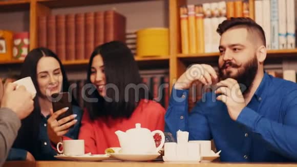 一群朋友在一张桌子旁的餐馆里休息女孩们看着电话笑着那家伙说了很多视频的预览图