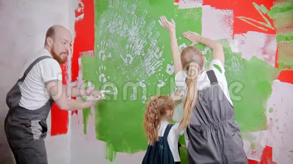一家人玩得很开心用自己的手在白色的油漆上画着绿色的墙视频的预览图