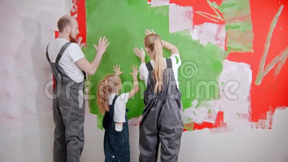 幸福的家庭正在把他们的白色手印涂在绿色的墙上视频的预览图