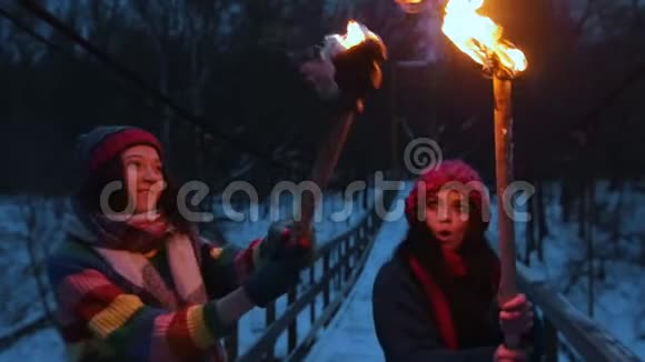 两个微笑的年轻女子站在冬天的森林里手里拿着火把视频的预览图