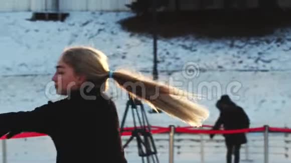 一个年轻女子职业花样滑冰运动员在户外的冰场上旋转视频的预览图