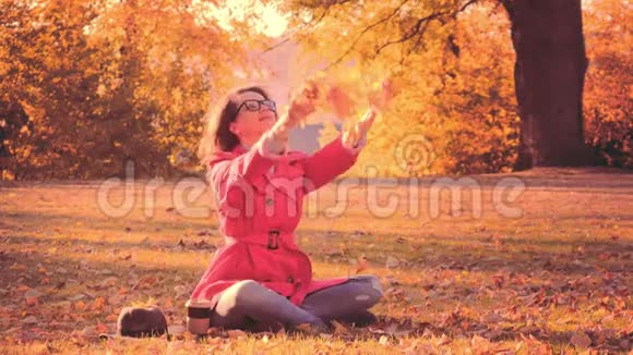 穿红色斗篷的女人在公园里扔秋叶视频的预览图