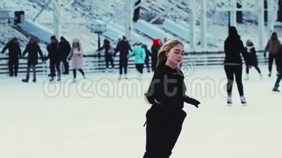 一个年轻漂亮的金发女人在阳光明媚的溜冰场上滑冰视频的预览图