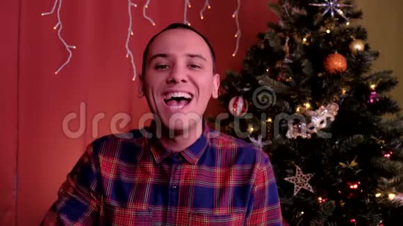一个男人看着相机笑着看圣诞节背景中的圣诞树节日圣诞节和视频的预览图