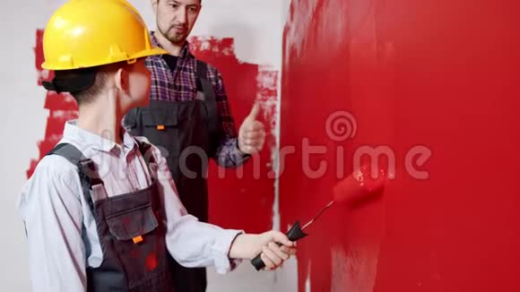 幸福的家庭修理公寓父亲解释他的儿子如何正确地粉刷墙壁视频的预览图