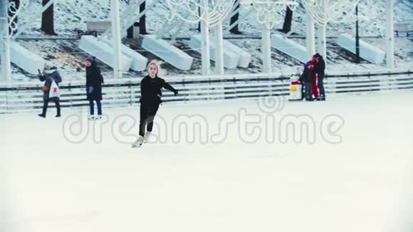 一个年轻的金发女人在溜冰场上和其他人在户外滑冰视频的预览图