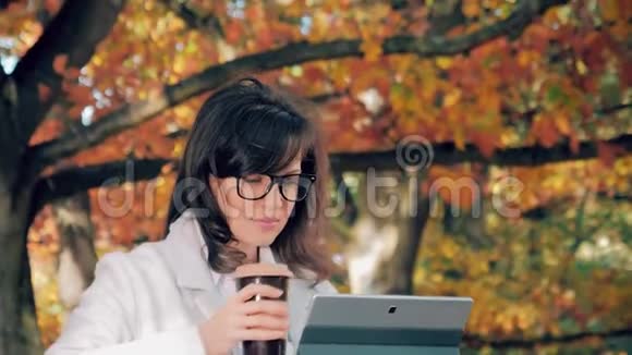 女人在外面喝咖啡拿着笔记本视频的预览图