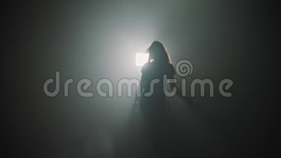 一个年轻迷人的女人从烟雾中走出来开始在明亮的灯光下跳舞视频的预览图