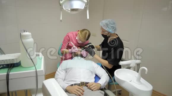 女牙医助理做男性病人在牙科中清洁牙齿视频的预览图