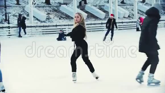 一位年轻的金发女子职业花样滑冰运动员在户外冰场上视频的预览图