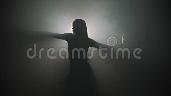 一个年轻迷人的女人的剪影她的手在明亮的灯光背景下跳舞视频的预览图