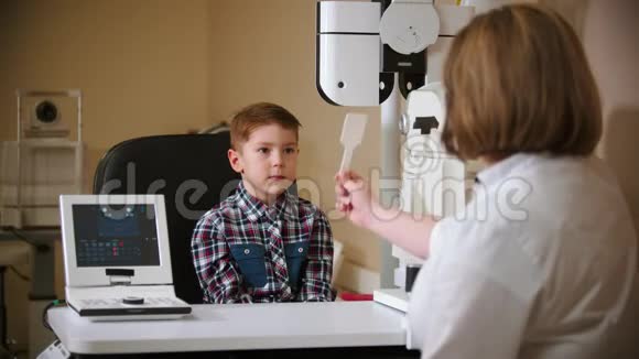 眼科诊所的一种治疗方法成熟的女医生和一个小男孩坐在桌子旁给男孩一个眼罩视频的预览图