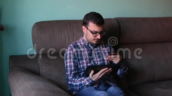 年轻人用平板电脑用信用卡付款视频的预览图