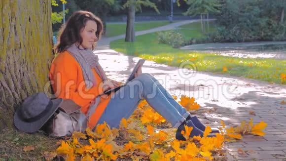 在公园里拿着笔记本电脑工作的女人城市里美丽的秋天视频的预览图