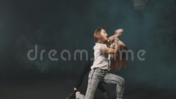 两个年轻女子在黑暗的工作室里训练舞蹈视频的预览图