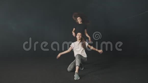 两名年轻女子在黑暗工作室训练同步舞蹈编排视频的预览图